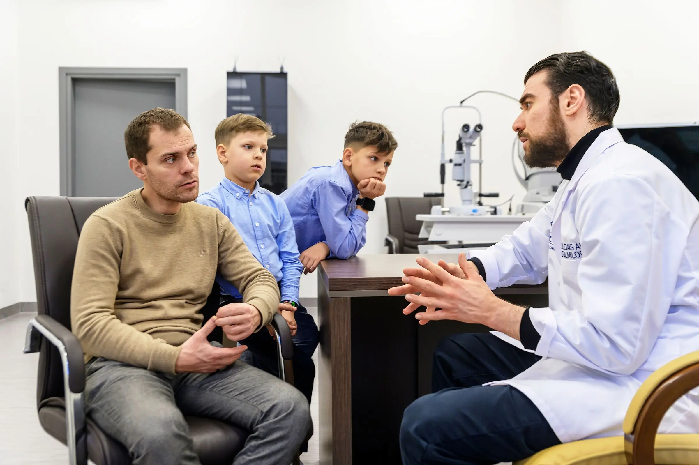 Dr. Ali advising a father and his two sons in his consulting room